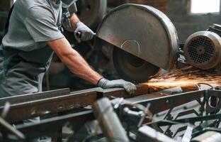 Cutting ,the ,metal with a saw. Close up view of man that is working at the factory photo