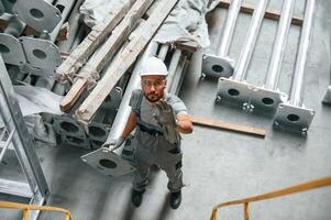 Top, view. Making gesture by hands. Young factory worker in grey uniform photo