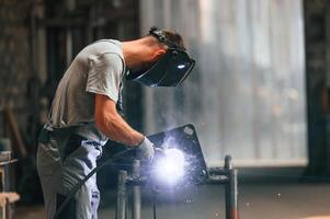 Process of ,welding. Young factory ,worker in grey uniform photo