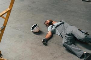 Accident, male, factory worker fell, without consciousness, lying down on the floor photo