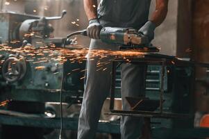Polishing, the, surface, with angle grinder. Close up view of man that is working at the factory photo