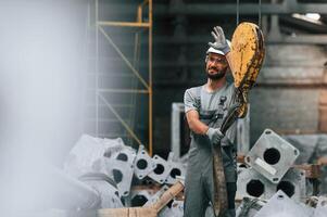 Using ,crane ,hook.. Young factory worker in grey uniform photo