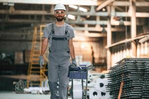 Front ,view,, walking forward. Young factory worker in grey uniform photo