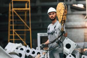 Using ,crane hook.. Young factory worker in grey uniform photo