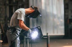 Process, of, welding. Young factory worker in grey uniform photo