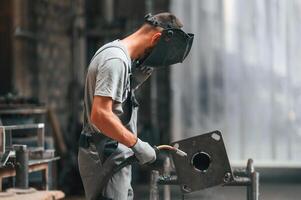 Process of ,welding. Young factory worker in grey uniform photo