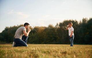 Talking by using string can phone. Father and little son are playing and having fun outdoors photo