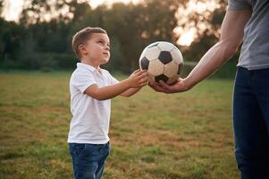 Boy ,is taking ,soccer ball. .Father and little son are playing and having fun outdoors photo