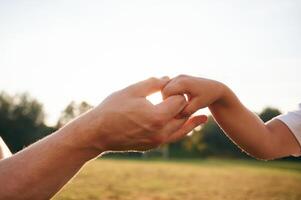 Beautiful sunlight. Close up view, of dad and his little son hands that are holding each other photo