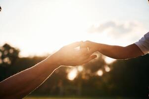 Beautiful sunlight... Close up view of dad and his little son hands that are holding each other photo