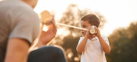With, string ,can phone. Father and little son are playing and having fun outdoors photo