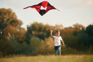 Little ,boy is playing outdoors at daytime. Standing, having fun with kite photo