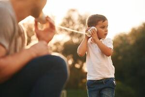 With string can phone. ..Father and little son are playing and having fun outdoors photo