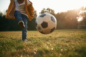 Grassy ,ground, ,with soccer ball. Little boy is playing outdoors at daytime photo