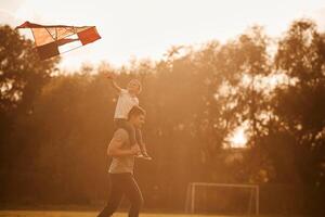 Red colored kite in ,hands. Father and little son are playing and having fun outdoors photo