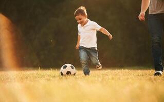 Activity,, running and playing soccer. Father and little son are playing and having fun outdoors photo