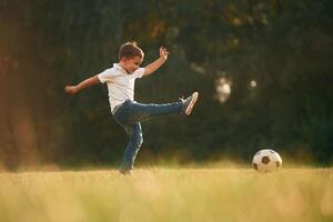 Side, view, playing soccer. Little boy is playing outdoors at daytime photo