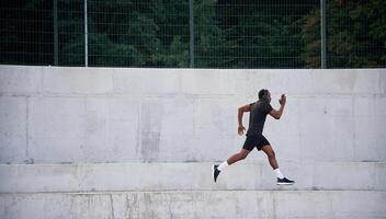 Side view. Sportive black man is running,, morning routine photo