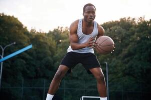 Playing, the game. Young black man is with basketball ball outdoors photo