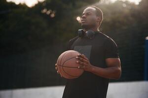 Sunlight outdoors. Young black, man is with basketball ball photo
