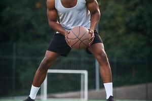 Front ,view. Young, black man is with basketball ball outdoors photo