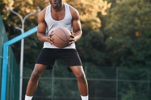 Front view.. Young black ma,n is with basketball ball outdoors photo