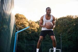 Photo, in motion. Young ,black man is with basketball ball outdoors photo