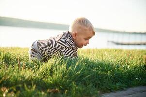 Cute little, boy is having fun outdoors on the ground with green grass photo