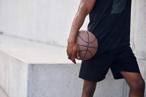 Close, up view. Young black man is with basketball ball outdoors photo