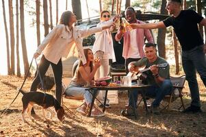 Doing cheers with bottles of beer.,, Group of friends are together in the forest photo
