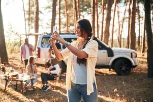 Woman is taking photo of nature. Group of friends are together in the ,forest