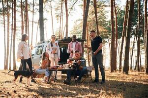 Doing cheers with bottles of beer. Group of friends are together in ,the, forest photo
