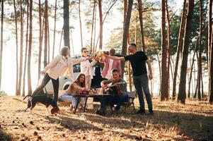 Doing cheers ,with ,bottles of beer. Group of friends are together in the forest photo