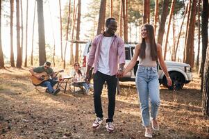 Couple ,,are holding each other by the hands, walking. Group of friends are together in the forest photo
