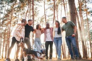 Standing, fun, with, dog. Group of friends are together in the forest photo