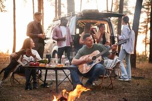 Acoustic, guitar, player. Group of friends are together in the forest photo