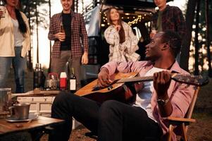 Acoustic, guitar ,player. Group of friends are together in the forest photo