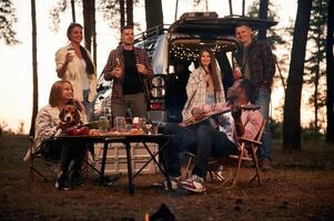 By the table at, evening time. Group of friends are together in the forest photo