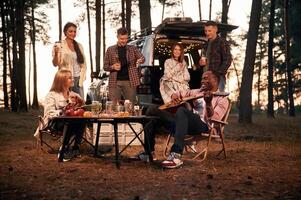 Evening time, by ,the table. Group of friends are together in the forest photo