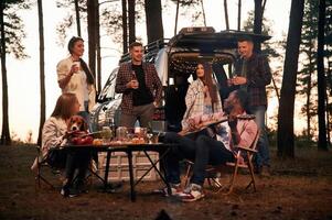 By the table,, at evening time. Group of friends are together in the forest photo