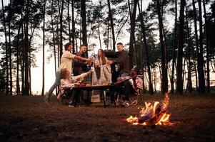 Beautiful bonfire, at evening time. Group of friends are together in the forest photo
