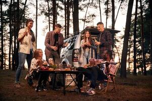 Evening time,, by the table. Group of friends are together in the forest photo