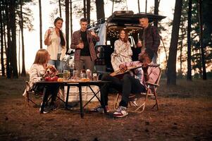 Evening, time,, by the table. Group of friends are together in the forest photo