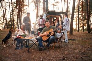 Acoustic, guitar player.. Group of friends are together in the forest photo