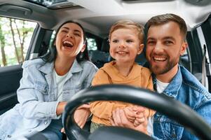 Family of father, mother and little son ,are ,sitting in the modern car photo