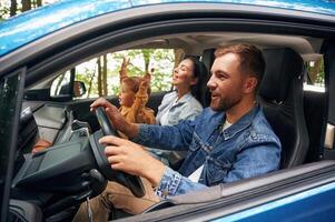 Side ,view, smiling... Family of father, mother and little son are sitting in the modern car photo