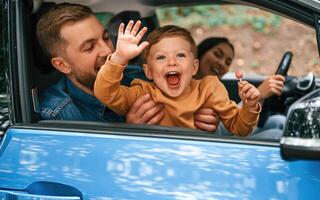 Family, of father, mother, and little son are sitting in the modern car photo