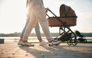 View from below of legs,. A young couple with a baby pram is walking together photo