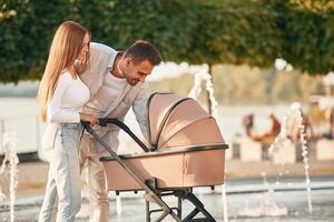 A young couple with a baby, pram, is walking together photo