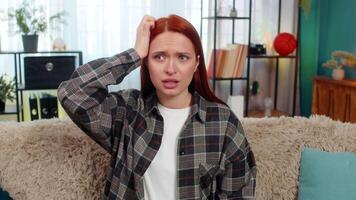 Woman sitting on sofa holding head looking confused and lost not knowing what to do in hard moment video